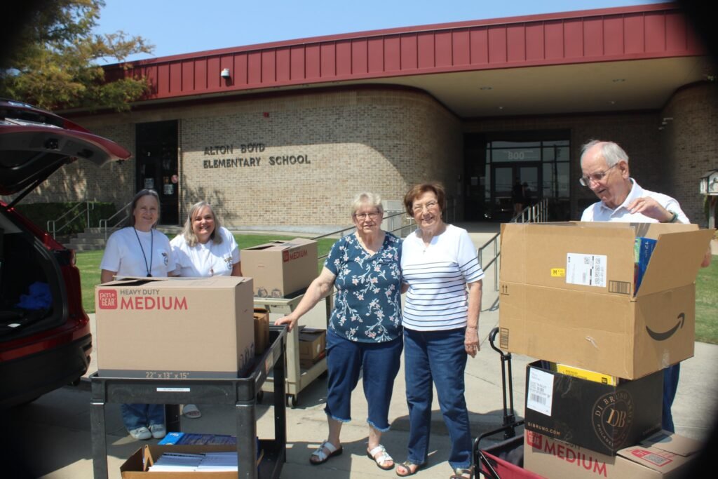 A group with boxes of donated supplies outside Boyd Elementary School.